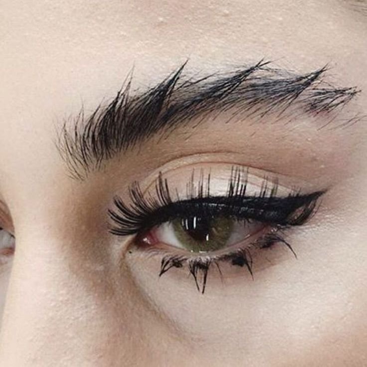 Thin arched brows and drawn lower lashes